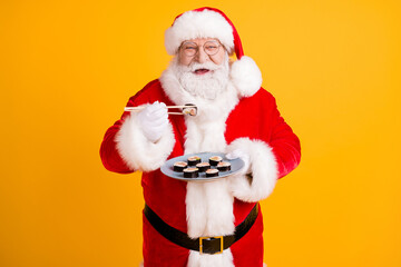 Portrait of his he nice cheerful white-haired Santa enjoying eating domestic gourmet sushi roll...