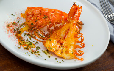 Appetizing cut in half grilled shrimps served on white plate