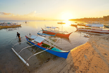 Beautiful colorful sunset on the seashore with fishing boats. Philippines, Siargao Island.