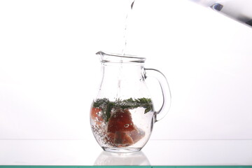 a carafe of water grapefruit and mint stands on a white background