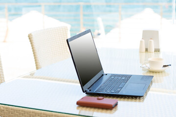Workplace in a cafe with a sea view. Man working on a laptop in a cafe. Copy space. Mock up.