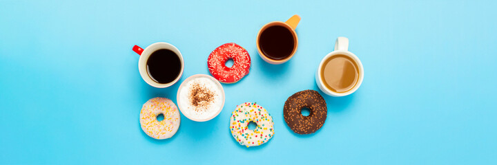 Tasty donuts and cups with hot drinks, coffee, cappuccino, tea on a blue background. Concept of sweets, bakery, pastries, coffee shop, meeting, friends, friendly team. Banner. Flat lay, top view