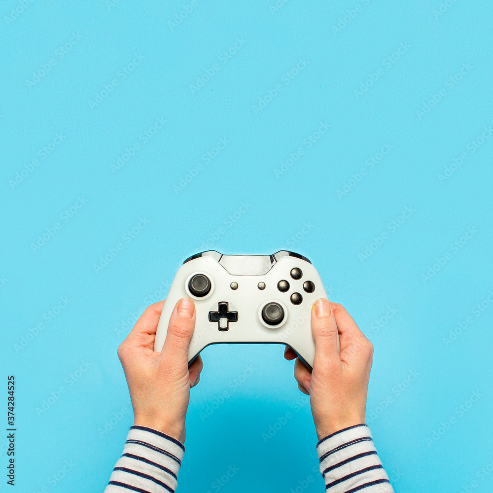 Wall mural hands holding a gamepad on a blue background. banner. concept games, video games