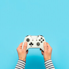 Hands holding a gamepad on a blue background. Banner. Concept games, video games © Alex