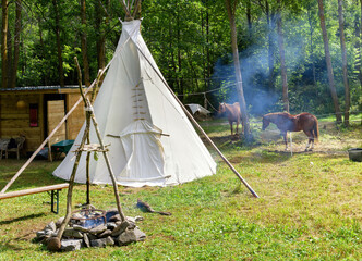 Tepee and camp fire with horses at a country cabin © photology1971