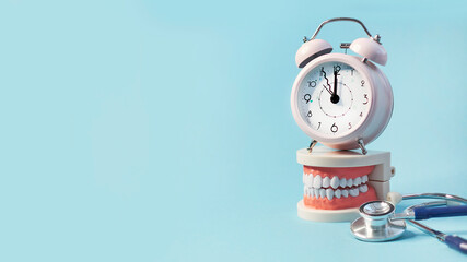 White teeth model with alarm clock and stethoscope on blue background. me to dental health. Dentist...