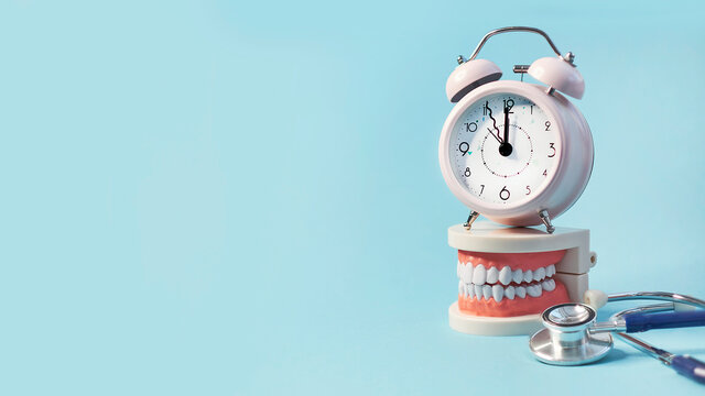 White teeth model with alarm clock and stethoscope on blue background. me to dental health. Dentist day concept. copy space for text.
