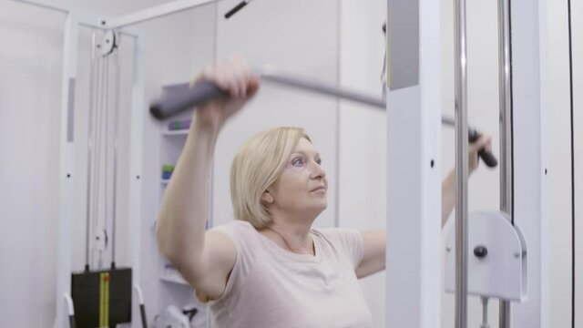 Senior woman doing pulldown exercise in gym, health and beauty care at old age