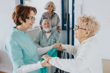 Fototapeta premium Smiling nurse holds an elderly lady's hands, helping her