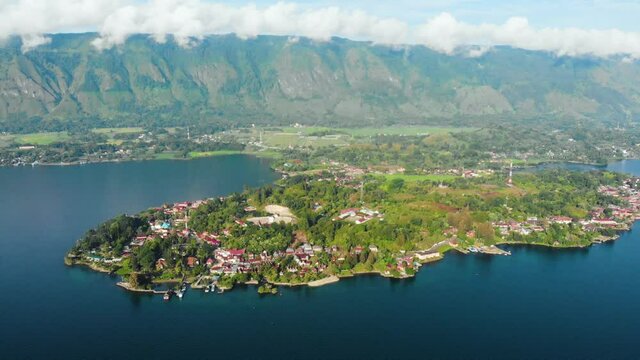 Aerial: flying over lake Toba and Samosir Island Sumatra Indonesia. Huge volcanic caldera water ecosystem, lush green equatorial forest.