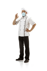 Cooker, chef, baker in uniform and protective face mask isolated on white background. Young man, restaurant cooker's portrait. Business, foor, professional occupation, emotions concept. Copyspace for