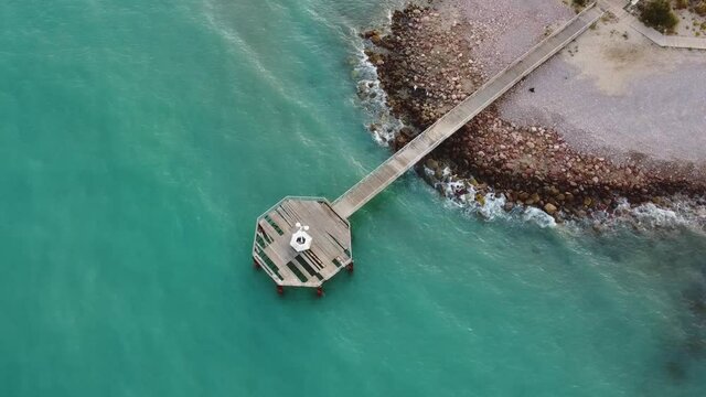 Vista a&eacute;rea de drone sobre el mar con un hermoso paseo de madera al fondo la playa
