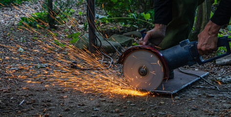 Cutting metal plate with an angle grinder. Close-up. Disc rotates and cuts metal. Sparks fly in all...