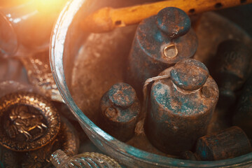 Old rusty iron weights and a wooden flute in a metal plate with other retro furniture on the countertop at antique bazaar. Shopping at bazaar concept.