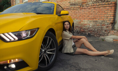 Fototapeta na wymiar Young woman sits near yellow sport car.
