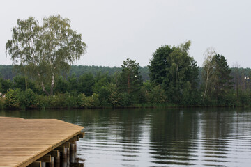 Wooden pier on a lake and a water reflection of a forest.