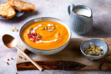 Vegetarian autumn pumpkin and carrot soup with cream, seeds and spices. Fall and winter comfort, healthy slow food