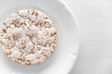 Close-up round slice of dietary crunchy bread on plate on the kitchen table. View from above.