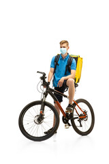Deliveryman in face mask with bicycle isolated on white studio background. Contacless service during quarantine. Man delivers food during isolation. Safety. Professional occupation. Copyspace for ad.