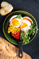 Healthy food Super Breakfast concept  fried eggs and micro-green salad with corn and tomato in Skillet iron pan with copy space