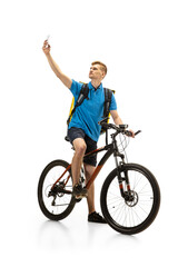 Taking selfie. Deliveryman with bicycle isolated on white studio background. Contacless service during quarantine. Man delivers food during isolation. Safety. Professional occupation. Copyspace for ad