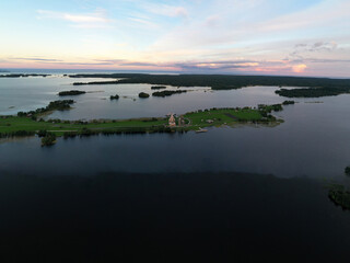 panoramic view of the lake with many islands on one of them there is an ancient temple made of wood at sunset filmed from a drone