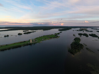Fototapeta premium panoramic view of the lake with many islands on one of them there is an ancient temple made of wood at sunset filmed from a drone