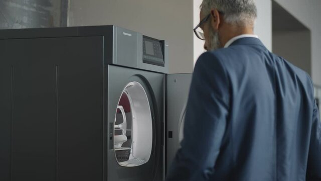 Handsome Mature Businessman Taking Clean Shoes From Cloth Dryer At Home