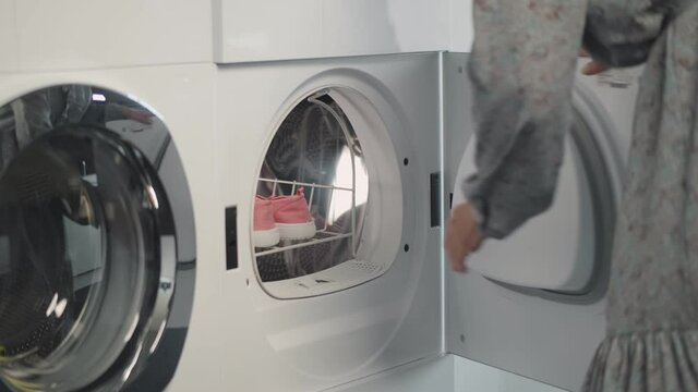 Close up of woman opening cloth dryer and taking clean shoes
