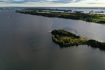 panoramic view of the lake with many islands on one of them there is an ancient temple made of wood at sunset filmed from a drone