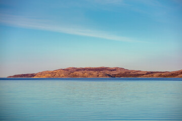 Obraz premium Fjord and rock on horizon. Minimalist landscape. Rocky seashore in the evening. Beautiful nature of Norway. Picturesque Scandinavian landscape. Lofoten islands, Norway, Europe