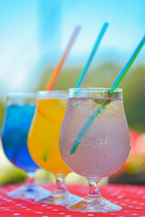 Three ice soft drinks with soda water, refreshing summer beverage. Alcohol cocktail with ice in a glass outside.