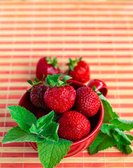 bright red strawberries in a bowl decorated with mint, copy space, healthy nutrition concept, poster with summer berries