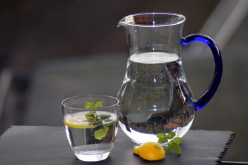 Closeup shot of fresh water with lemon and mint in a glass next to a decanter
