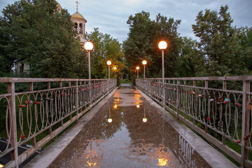 A small pedestrian bridge illuminated by lanterns.