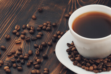 A cup of coffee with coffee bean on wooden background