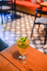 Refreshing cold citrus drink with mint. Cold summer beverage served in a glass. ALcohol cocktail on a wooden table