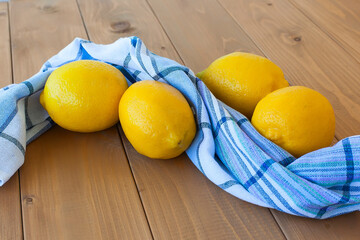 close up of four yellow lemons on an old wooden background and a towel