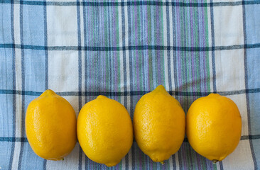close up of four yellow lemons on an old wooden background and a towel