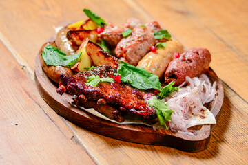 Georgian dinner. Meat, sausages and baked potatoes with fresh greenery served on a wooden board.