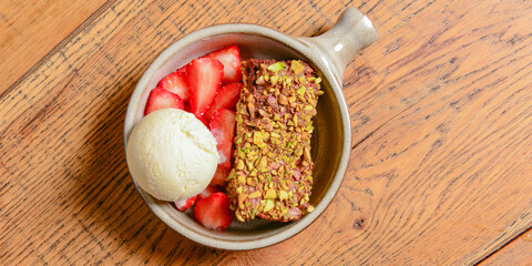 Brownie dessert with ice cream and fresh organic strawberry. Served in a traditional bowl. Georgian cuisine concept.