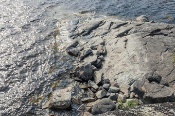 Top view on textured grey rocks on a shore surrounded by water of Ladoga lake in Karelia