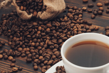 White Cup Of Coffee On Old Rustic Table With Burlap Sack And Beans