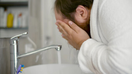 Obraz na płótnie Canvas Stout man in bathrobe Washing Face in Bathroom at Morning.