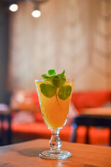 Refreshing cold citrus drink with mint. Cold summer beverage served in a glass. ALcohol cocktail on a wooden table