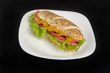 Mortadella and lettuce sandwich with oregano-covered bread, on a white plate and pepper sauce and mustard on a table with black towel, Selective focus.