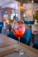 A glass with the red citrus cocktail. Alcohol summer beverage in a wine glass. Refreshing drink with ice.