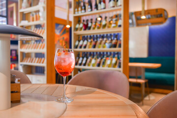 A glass with the red citrus cocktail. Alcohol summer beverage in a wine glass. Refreshing drink with ice.