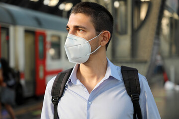 Fototapeta na wymiar Portrait of man waiting train with KN95 FFP2 protective mask at train station
