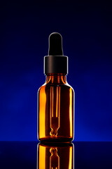 Glass bottle with cosmetic oil on dark background